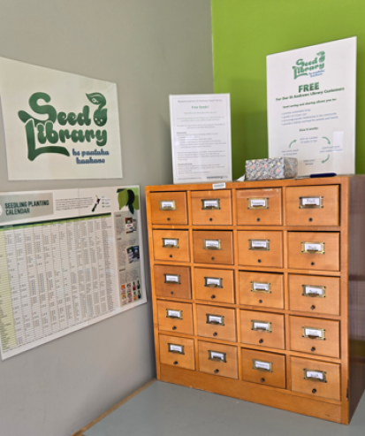 Picture of the repurposed wooden card catalogue cabinet now used to hold seeds. A planting calendar is on the wall next to it.